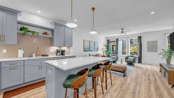 Une cuisine moderne avec des meubles gris, un grand îlot central et des tabourets de bar.