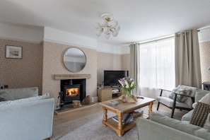 A living room with a fireplace, a television, and a sofa. - Orca Cottage, Seahouses, Northumberland (Seahouses)