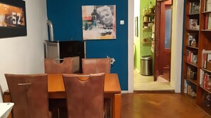 A dining area with a table and chairs, a refrigerator, a poster on the wall, and a bookshelf in the background. - Apartment 'Für 2 Personen 63 M²' with Wi-Fi (München)