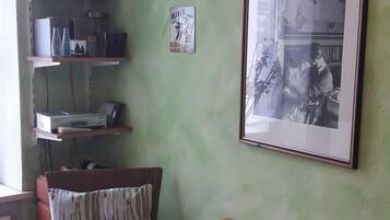 Ein Zimmer mit grüner Wand, einem gerahmten Foto und Regalen mit verschiedenen Gegenständen.