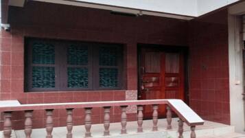 A building with a red brick facade, a wooden door, and a balcony with a balustrade.
