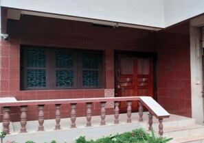 A building with a red brick facade, a wooden door, and a balcony with a balustrade.