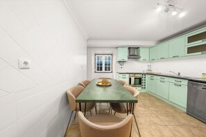 Een moderne keuken met een eettafel, stoelen en lichtgroene kastjes.