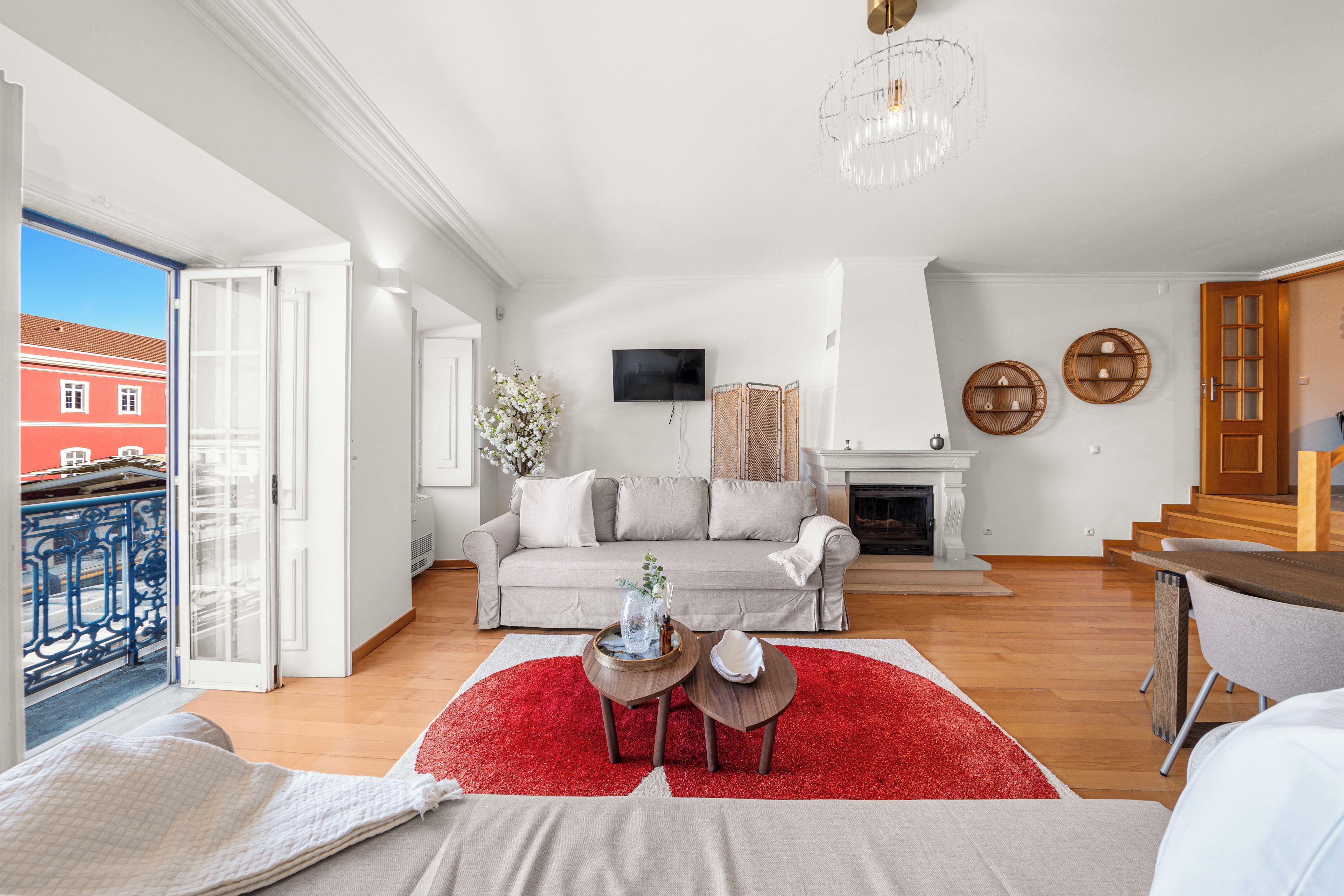 Een ruime woonkamer met een bank, een open haard, een televisie en een balkon met een hekwerk.
