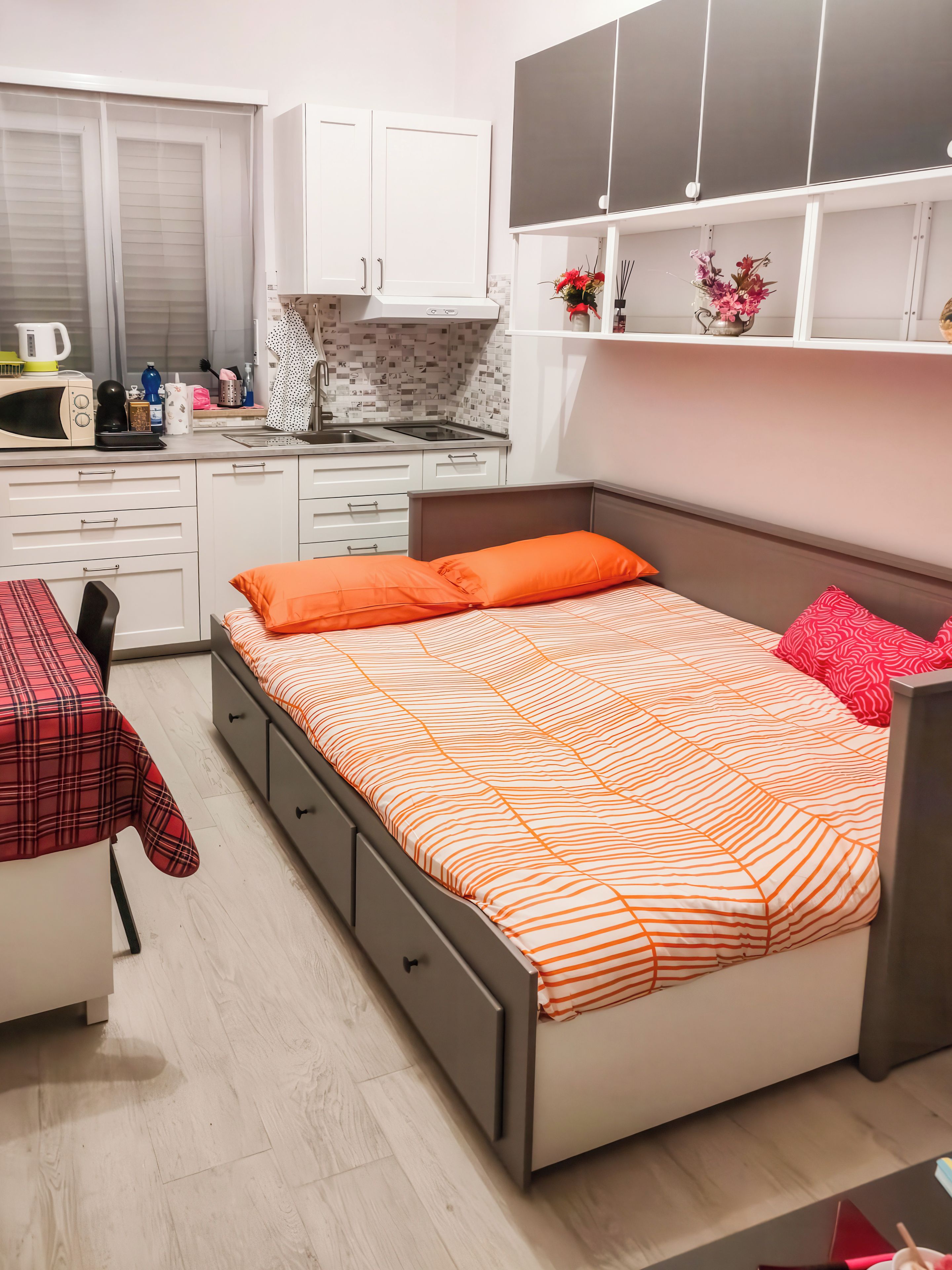 Un dormitorio con cama, escritorio y kitchenette.