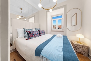 A modern bedroom with a large bed, a bedside table with a lamp, and a window with a view of buildings. - Penthouse with Terrace & Stunning View w/ AC (Lisbon)