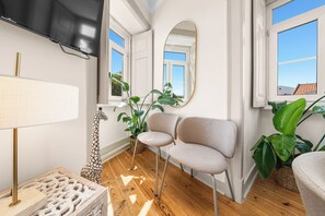 Ein modernes Wohnzimmer mit Holzboden, einer Couch, einem Fernseher und einem großen Spiegel.