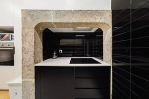 A kitchen with a stone archway, black backsplash, and a built-in stove. - Heart of Lisbon | Comfortable Stay for 10 w/AC (Lisbon)