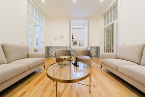 A spacious living room with a round glass coffee table, two sofas, and a large window with a view. - Heart of Lisbon | Comfortable Stay for 10 w/AC (Lisbon)