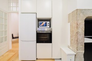 A modern kitchen with a built-in microwave, oven, and a stone feature. - Heart of Lisbon | Comfortable Stay for 10 w/AC (Lisbon)