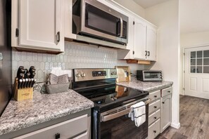 A kitchen with white cabinets, a stainless steel stove, a microwave, and a toaster. - 5br Family Escape, Hot Tub, Game Room, Sleeps 12 (McGaheysville)