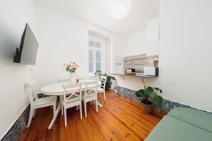A compact living space with a dining area, kitchenette, and a green sofa. - Elegant Central Lisbon Stay w/AC at Your Doorstep (Lisbon)