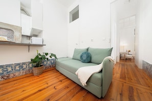 A modern living room with a sofa, a potted plant, and a wooden floor. - Elegant Central Lisbon Stay w/AC at Your Doorstep (Lisbon)