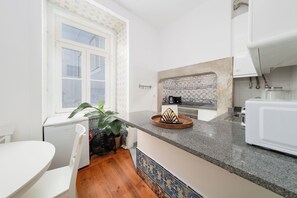 A modern kitchen with white cabinetry, a granite countertop, and a backsplash with blue and white tiles. - Elegant Central Lisbon Stay w/AC at Your Doorstep (Lisbon)