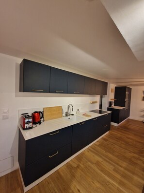 A modern kitchen with a central island, dark cabinetry, and a wooden floor. - Large, quiet house near Nantes (Vertou)