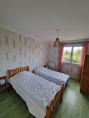 A room with two wooden beds, a bedside table, a lamp, and a window with curtains. - Large, quiet house near Nantes (Vertou)