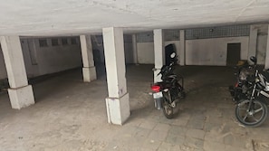 A parking area with concrete pillars and a motorcycle parked.