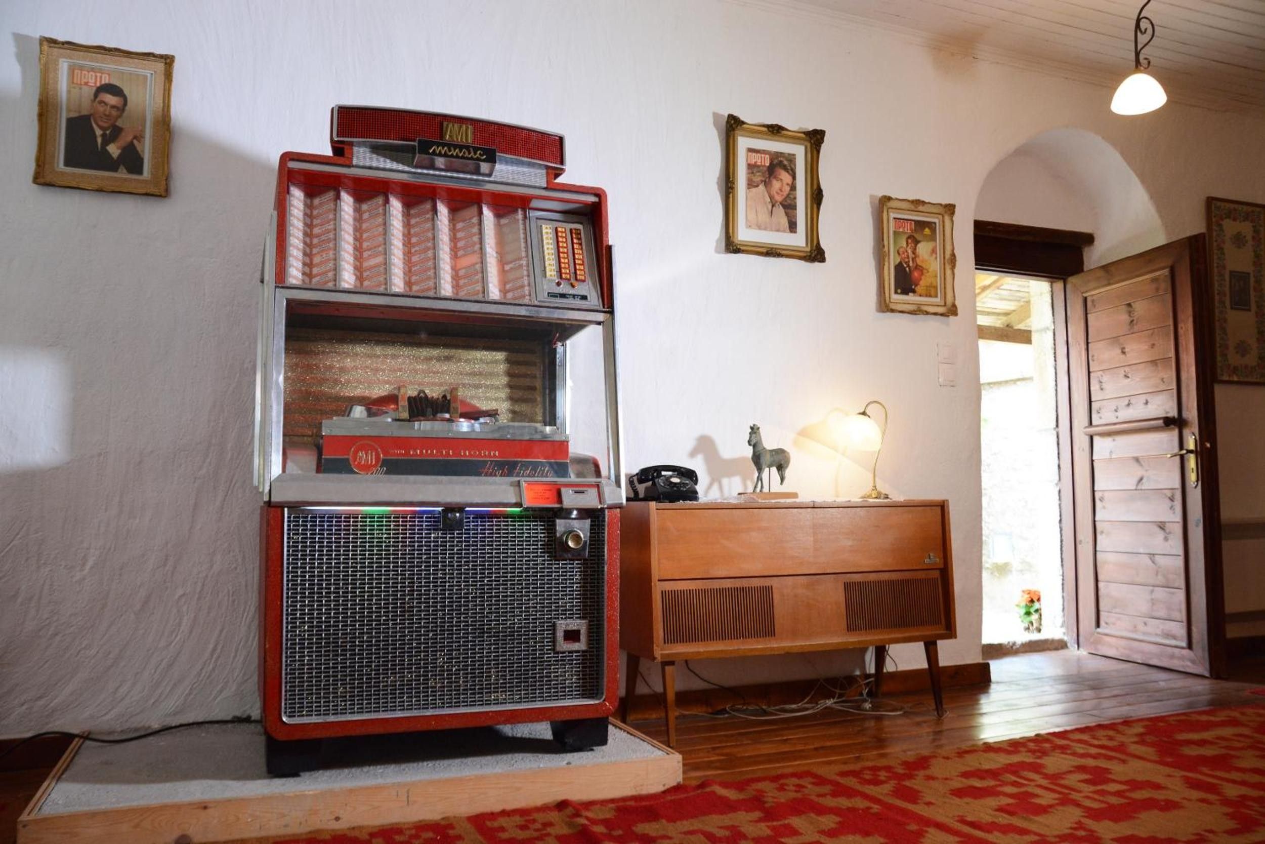 Ein Vintage-AMI-Jukebox in einem Raum mit Holzmöbeln, gerahmten Bildern an der Wand und einem gemusterten Teppich.