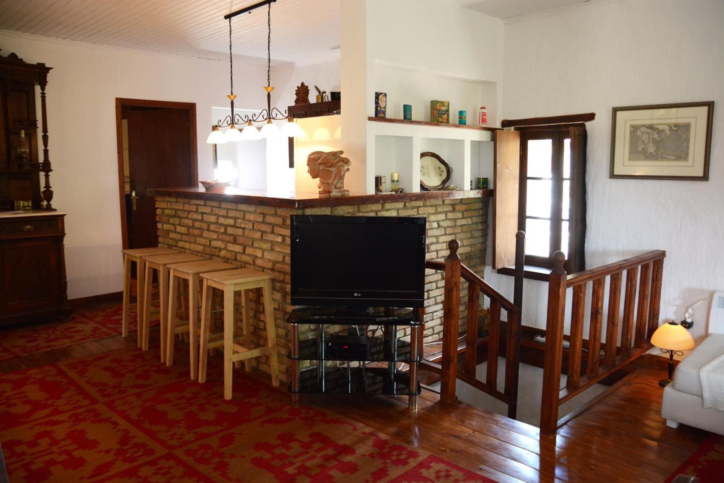 Een woonkamer met een open haard van baksteen, een televisie en een houten bar.