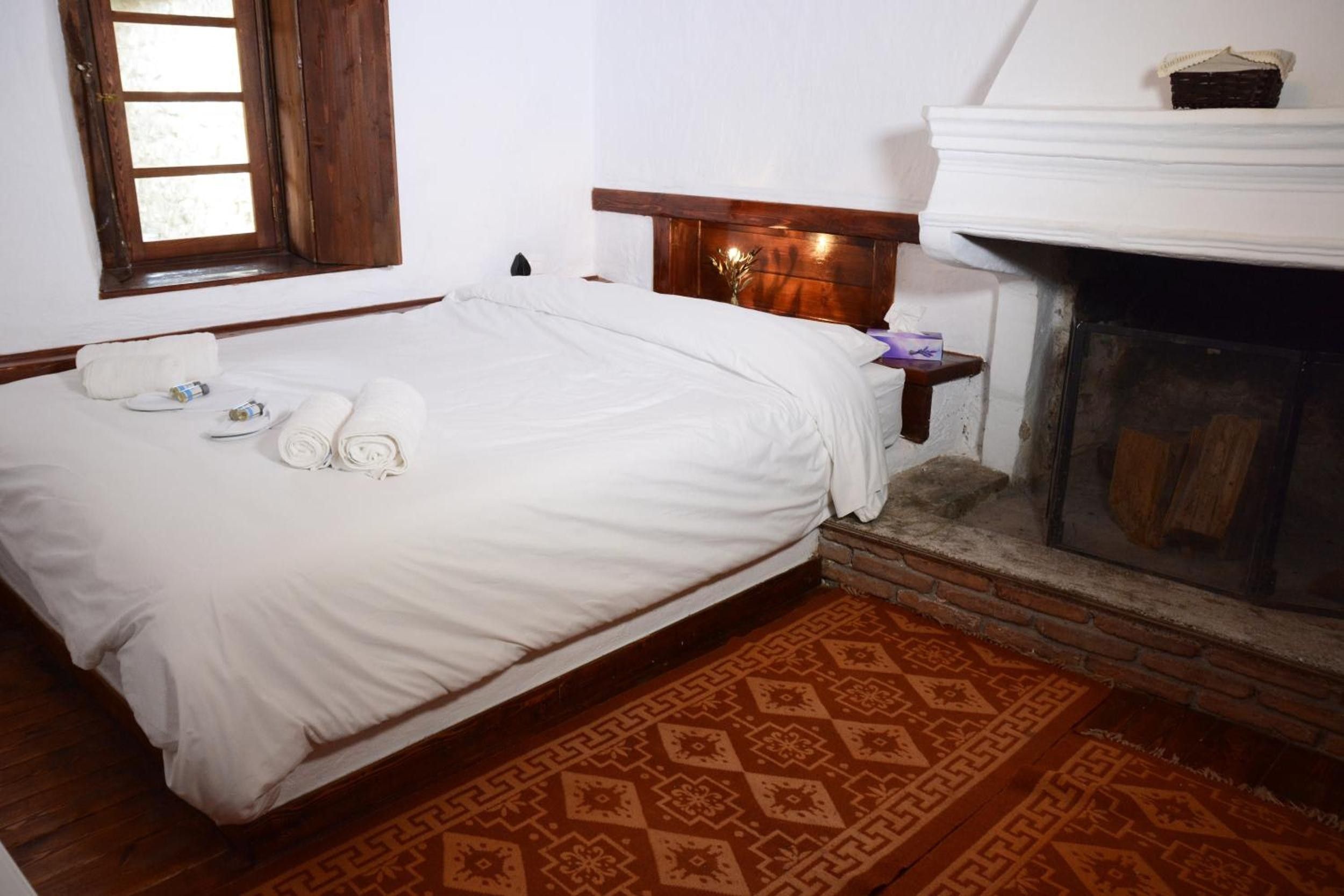 Un dormitorio con cama, chimenea, ventana y alfombra estampada.