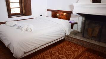 Un dormitorio con cama, chimenea, ventana y alfombra estampada.