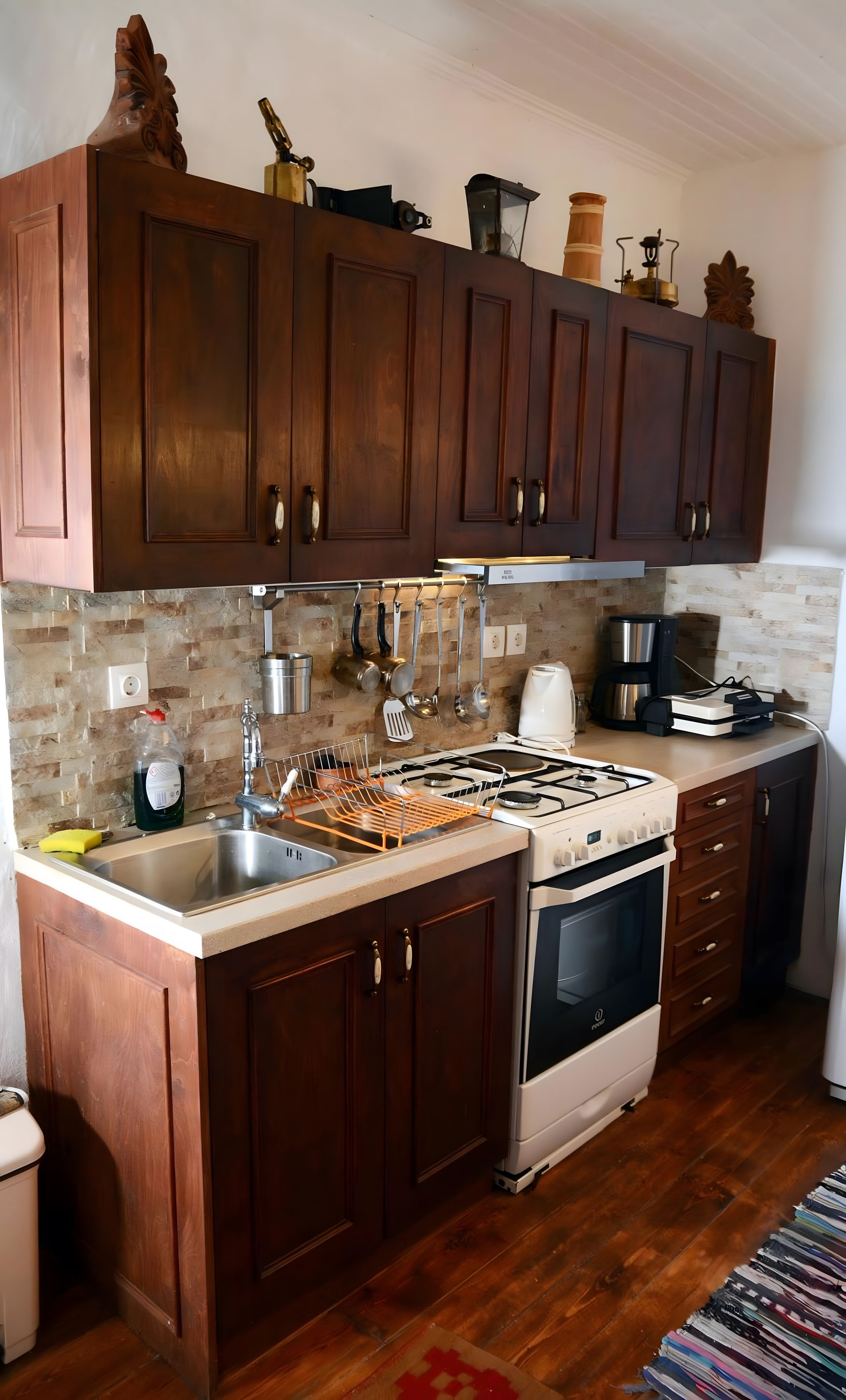 Una cocina con armarios de madera, estufa a gas, pileta y cafetera.