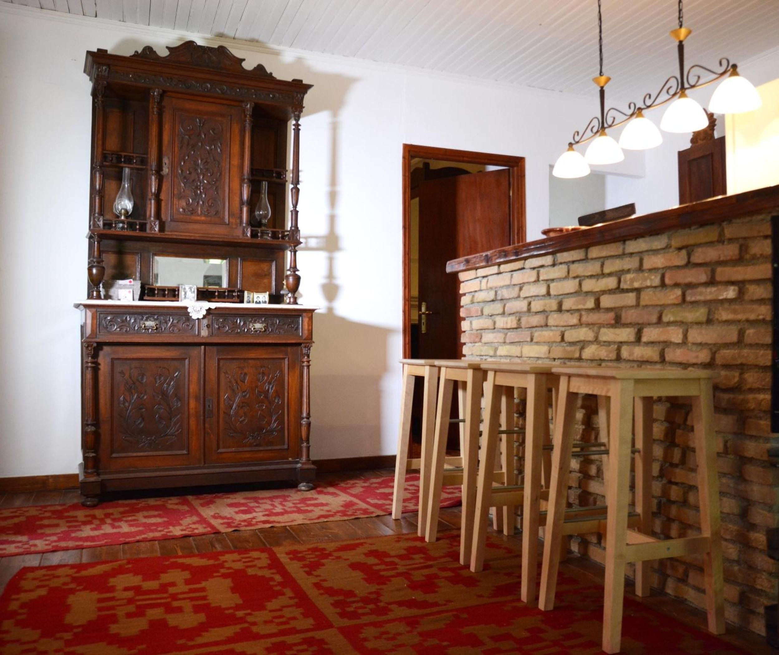 Een kamer met een houten kast, een bakstenen muur en een bar met krukjes.