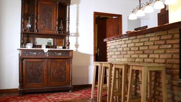 Een kamer met een houten kast, een bakstenen muur en een bar met krukjes.