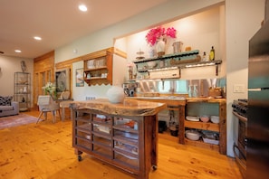 A kitchen with wooden cabinets, a central island, and a dining area with a sofa and table. - Stunning 3,000 sq ft Blue Ridge Pkwy Guest House 30 Acres/Pond/Hot Tub/Game Room (Floyd)