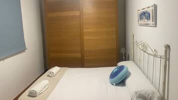 Una habitación de hotel con una cama, un armario de madera, un cuadro en la pared y una mesita de noche.