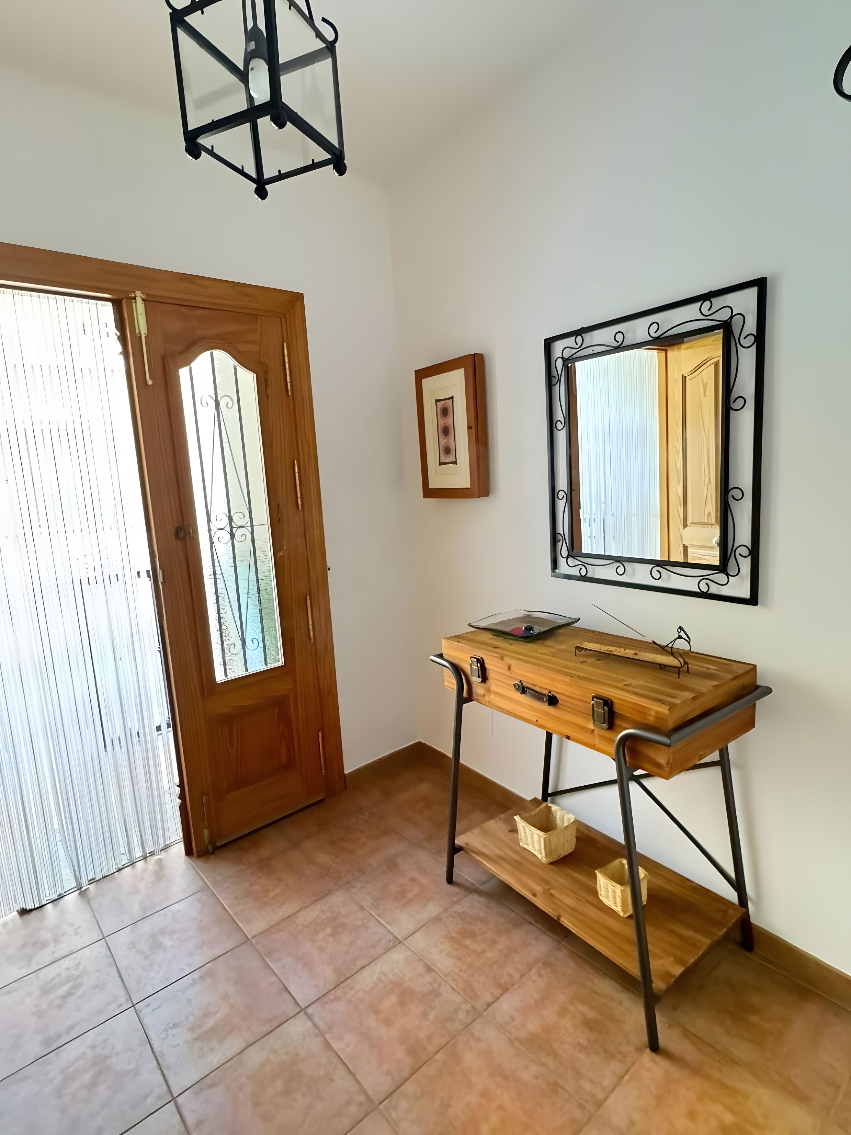 A room with a wooden desk, a mirror, and a door.