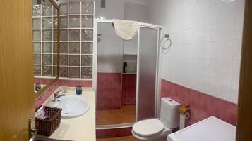 Un baño con lavamanos blanco, inodoro y zona de ducha.