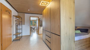 Ein modernes Interieur mit Holzböden, einem zur Essecke führenden Flur und einem Bett mit Kopfteil.