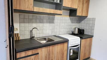 A kitchen with wooden cabinets, a stainless steel sink, a white stove, and a tiled backsplash.
