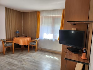 Een kamer met een eettafel, stoelen, een televisie en een telefoon.