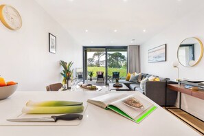 A modern living room with a dining area, a sofa, a coffee table, and a view of the outdoors. - Sea views with balcony & parking | 8 The Liner (Falmouth)