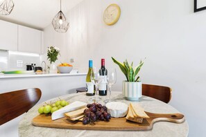 Una cucina moderna con un piano di lavoro in marmo, un tagliere di legno con formaggio, uva e cracker, e due bottiglie di vino.