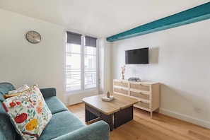Een woonkamer met een bank, een salontafel, een televisie en een raam met uitzicht.