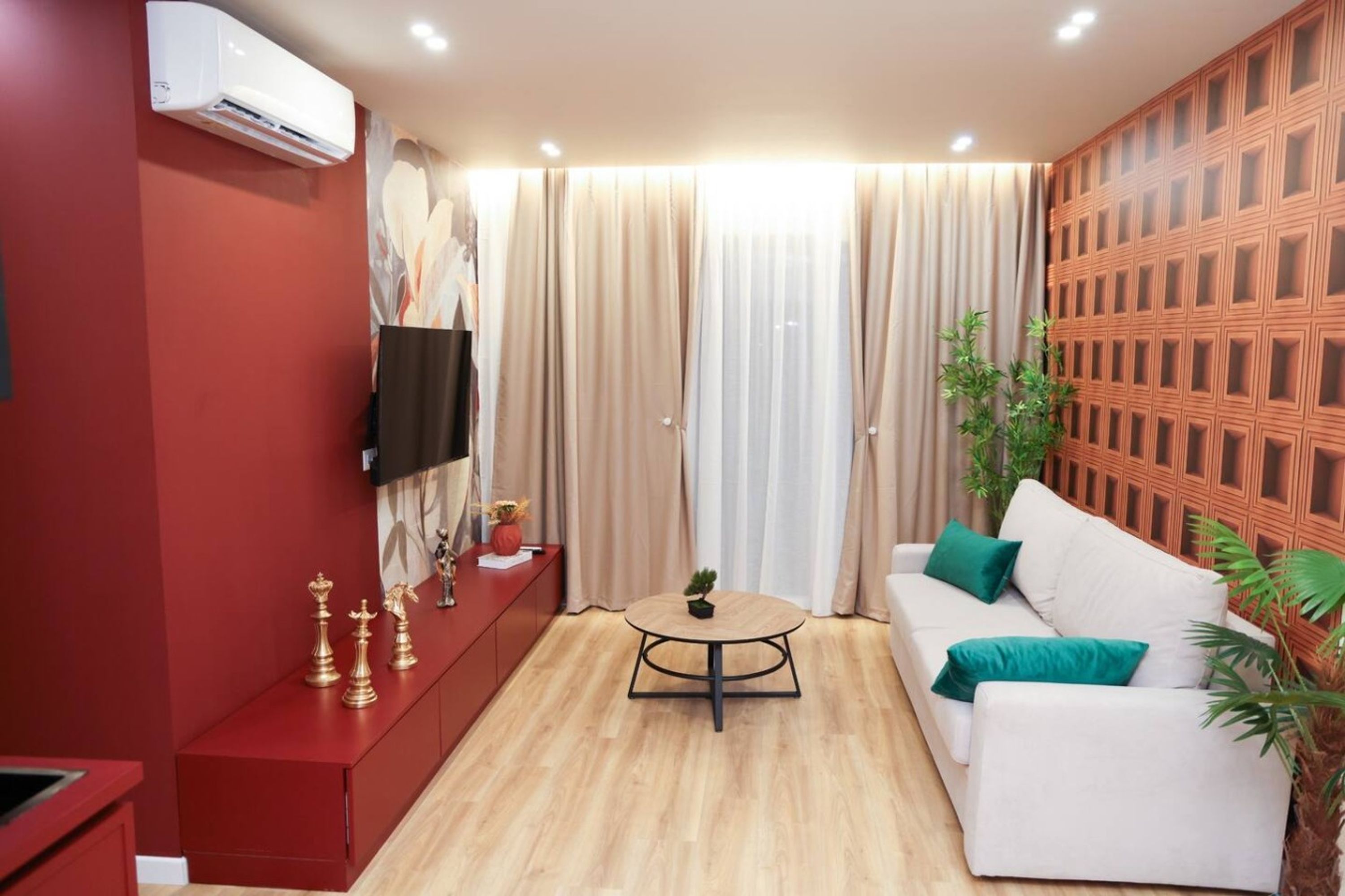 A modern living room with a red cabinet, a white sofa, a round coffee table, and a television mounted on the wall.