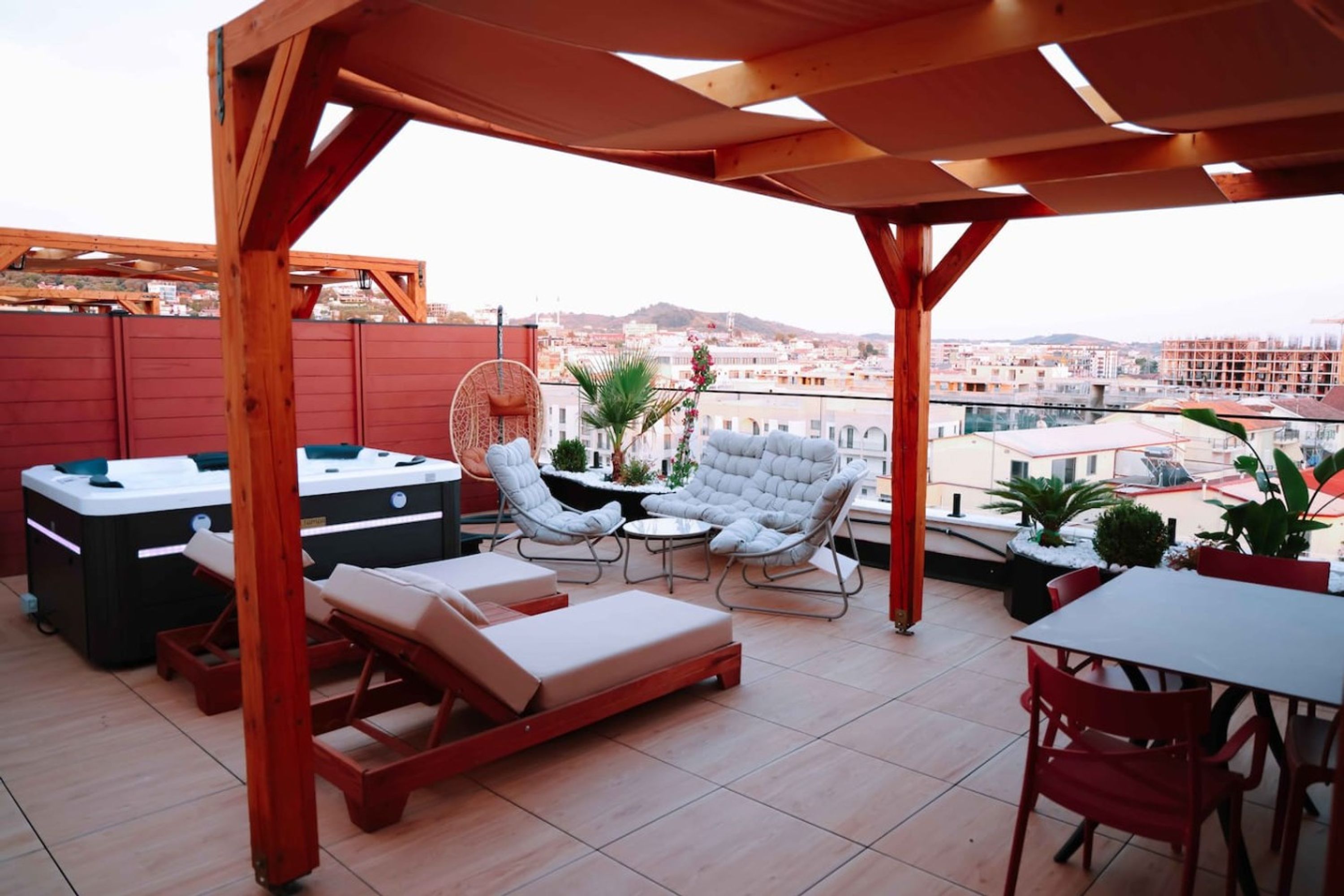 A rooftop terrace with outdoor furniture, a fan, and a view of the cityscape.