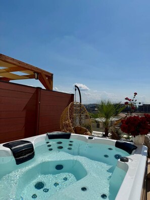 A hot tub with jets, a wooden pergola, a hanging chair, and a view of the cityscape. - Altamar Luxury Suites Penthouse - 102 (Golem)