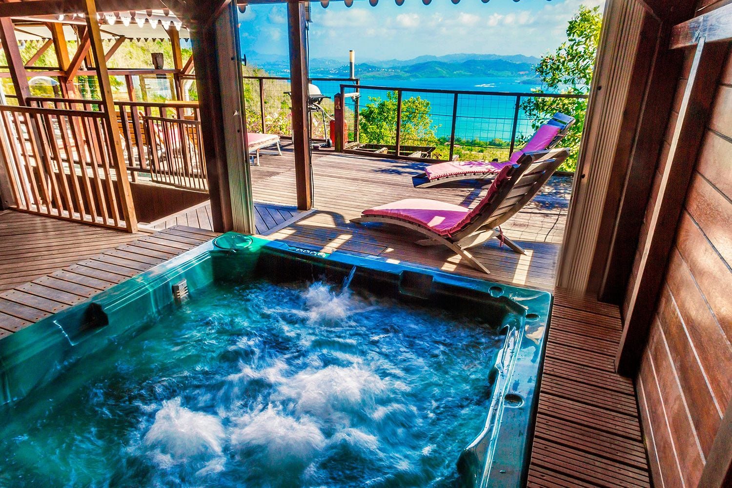 A hot tub on a wooden deck with a view of the sea.