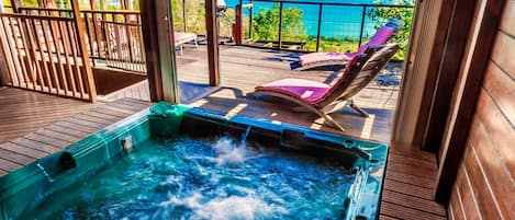 A hot tub on a wooden deck with a view of the sea.