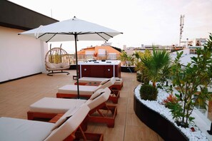 A rooftop terrace with lounge chairs, a hanging chair, a barbecue grill, and a large umbrella. - Altamar Luxury Suites Penthouse - 101 (Golem)