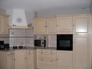 A kitchen with white cabinets, a microwave, an oven, and a coffee maker. - Country house 'Gîte Clos Saint Vincent' with Wi-Fi (Verdigny)