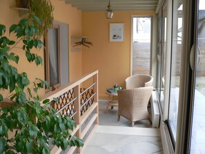 A room with a wicker chair, a small table, a hanging plant, and a framed picture on the wall. - Country house 'Gîte Clos Saint Vincent' with Wi-Fi (Verdigny)