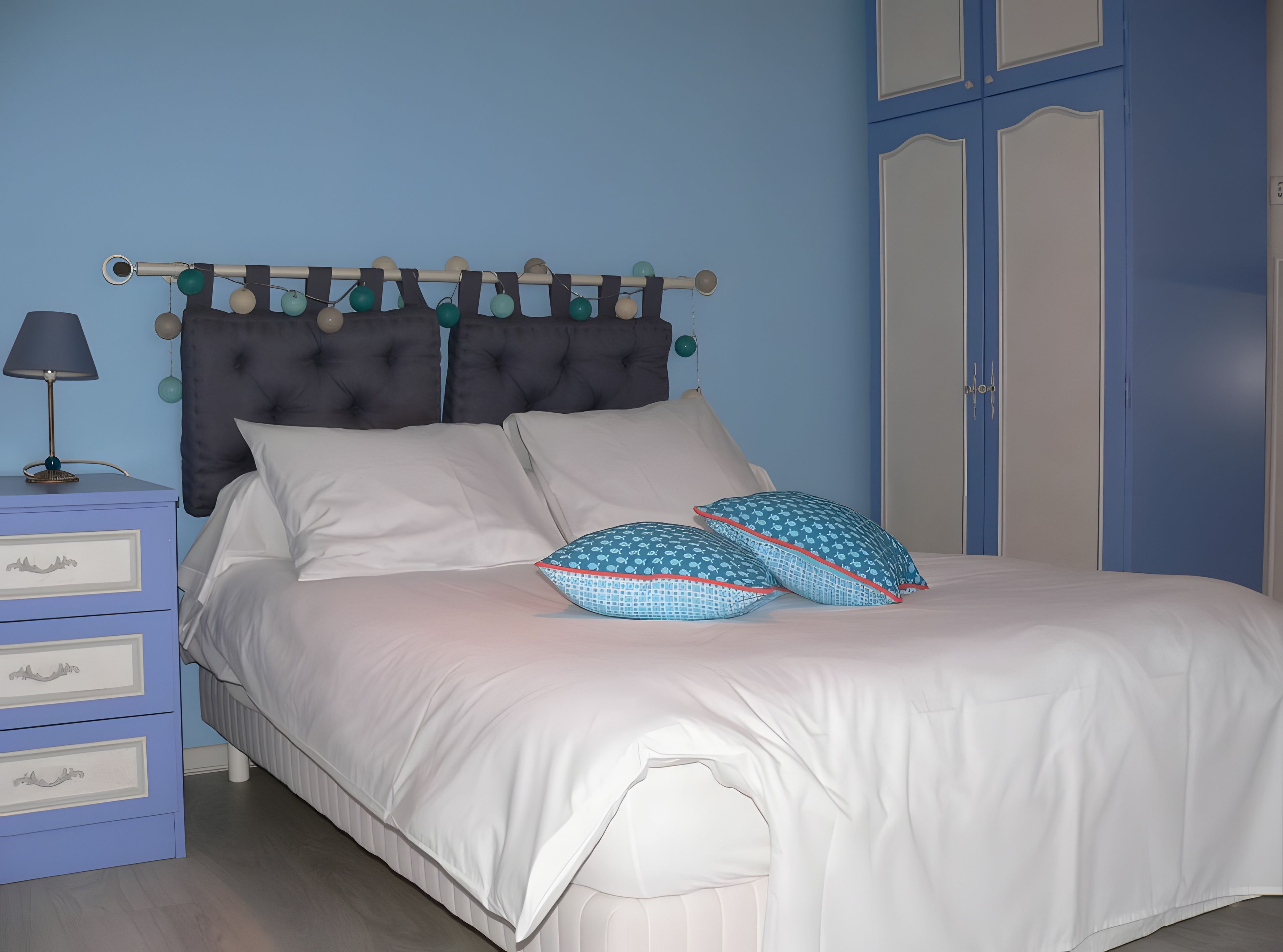 A bed with white bedding, a tufted headboard, and two patterned pillows.