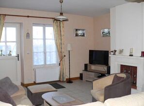 A living room with a fireplace, a television, and a sofa. - Country house 'Gîte Clos Saint Vincent' with Wi-Fi (Verdigny)