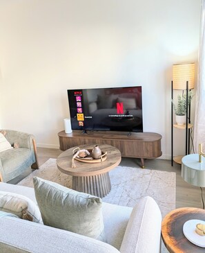 A modern living room with a flat-screen TV, a round coffee table, and a sofa.