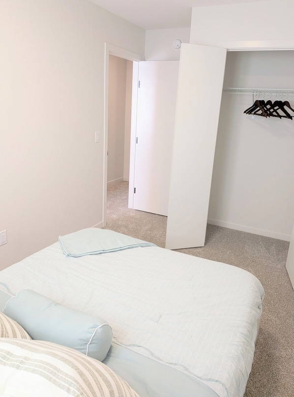 A bedroom with a bed, a closet, and a door leading to another room.